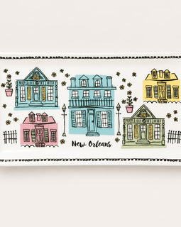A rectangular white ceramic serving platter featuring a colorful New Orleans-themed illustration of five houses in pastel blue, pink, yellow, and green, with the text 'New Orleans' in script.