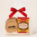 A New Orleans-themed gift basket featuring a bag of Aunt Sally's Creole Pralines and a set of cork coasters, wrapped in clear cellophane with a red ribbon and white paper shred.