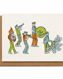 A square cream greeting card with a brown kraft envelope behind it, featuring a retro-style illustration of a marching band with instruments.
