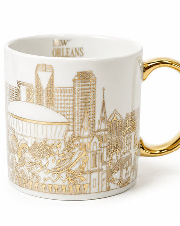A white ceramic coffee mug featuring a gold line-art illustration of the New Orleans skyline and the word 'NEW ORLEANS' printed inside the rim, with a polished gold handle.