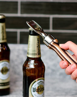 Pakka wood handle bottle opener with stainless steel head resting on a wooden surface