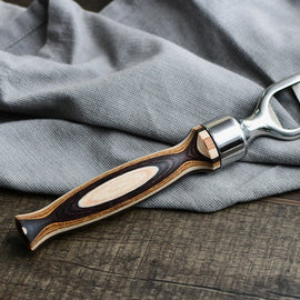 Pakka wood handle bottle opener with stainless steel head resting on a wooden surface