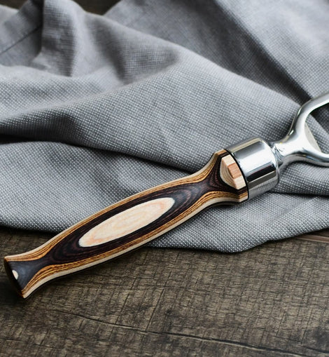 Pakka wood handle bottle opener with stainless steel head resting on a wooden surface