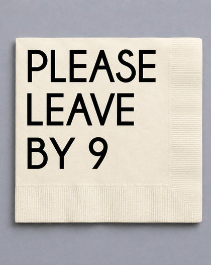An off-white paper napkin with black printed text reading 'PLEASE LEAVE BY 9' on a solid gray background.