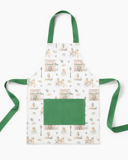 A white apron with a green neck strap and waist ties, featuring a repeating pattern of vintage illustrations of people sitting at tables and a large solid green front pocket.