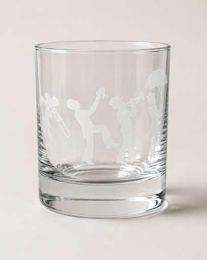 A clear glass rocks tumbler with frosted white etched silhouettes of people holding drinks, shown on a neutral light beige background.
