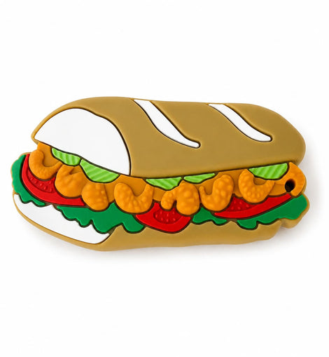 A po boy teether featuring a tan bread bun, orange shrimp, green lettuce, and red tomato slices, shown on a plain white background.