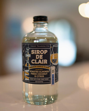 Bottle of Sirop Trading Co Sirop de Clair premium simple syrup with roasted almond, coconut, and citrus tasting notes, handcrafted in South Louisiana.