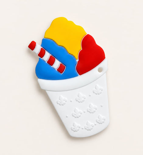 A silicone baby teether shaped like a snowball featuring yellow, blue, and red scoops with a red-and-white striped straw, set against a light beige background.
