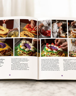 An open cookbook spread displayed on a light marble surface against a white background. The pages feature multiple color food photographs, a quote on the left page, and two columns of text.