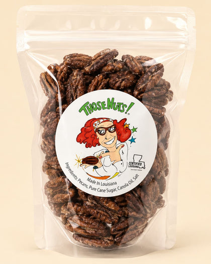 A clear stand-up pouch filled with roasted pecans, featuring a round white label with the brand name 'Those Muts!' and a cartoon illustration, set against a solid light beige background.