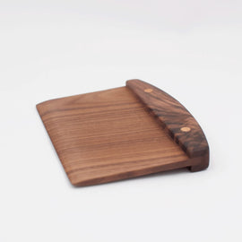 Handcrafted wooden walnut bench scraper with pinned handle on white background.