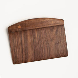 Handcrafted wooden walnut bench scraper with pinned handle on white background.
