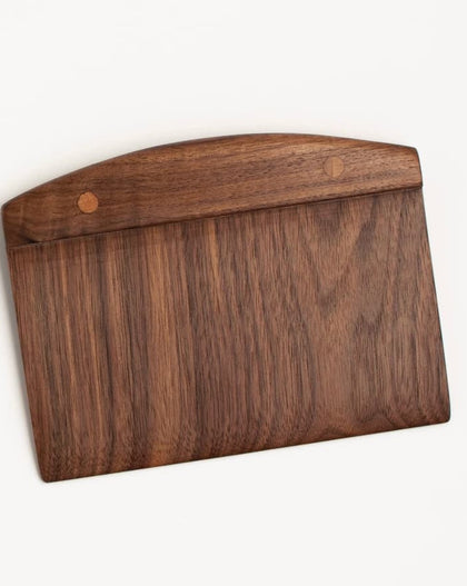 Handcrafted wooden walnut bench scraper with pinned handle on white background.