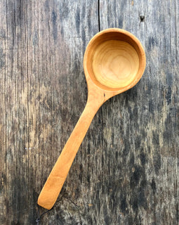 Handcrafted wooden ladle with hanging string on rustic background