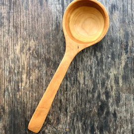 Handcrafted wooden ladle with hanging string on rustic background