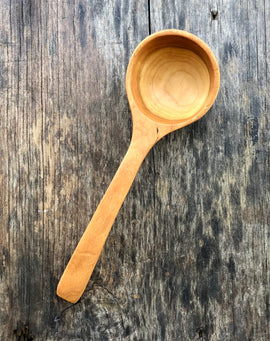 Handcrafted wooden ladle with hanging string on rustic background