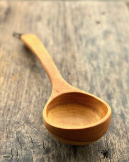 Handcrafted wooden ladle with hanging string on rustic background