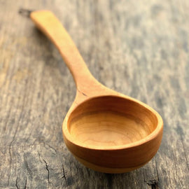 Handcrafted wooden ladle with hanging string on rustic background