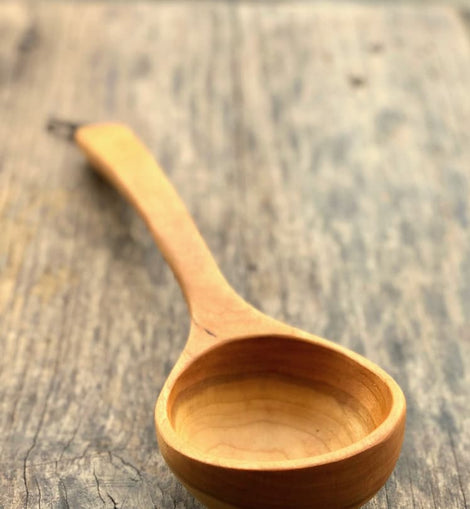 Handcrafted wooden ladle with hanging string on rustic background