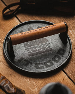 Cast iron skillet with wooden handle on a wooden surface, surrounded by rustic items.