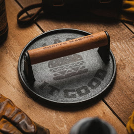 Cast iron skillet with wooden handle on a wooden surface, surrounded by rustic items.