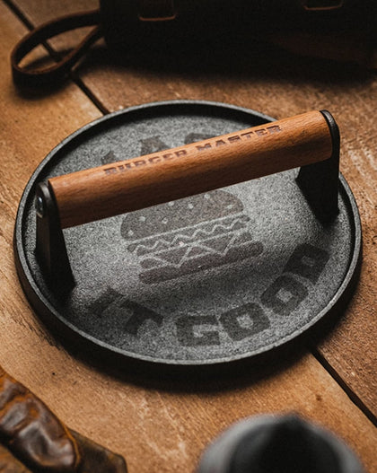 Cast iron skillet with wooden handle on a wooden surface, surrounded by rustic items.