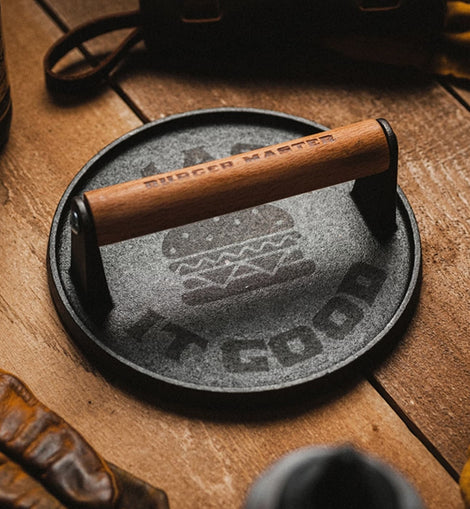 Cast iron skillet with wooden handle on a wooden surface, surrounded by rustic items.