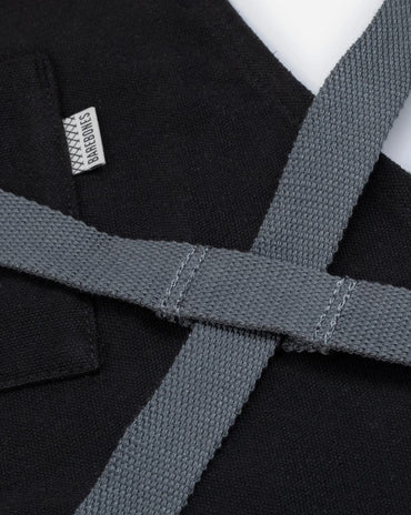 black canvas and leather chef apron with cross back straps, tool pockets, and metal hardware for cooking and grilling