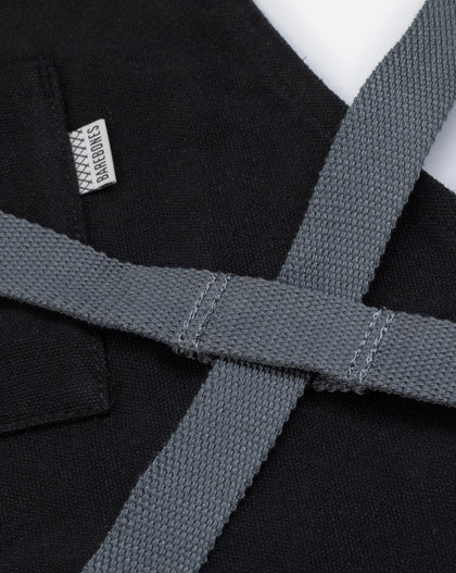 black canvas and leather chef apron with cross back straps, tool pockets, and metal hardware for cooking and grilling