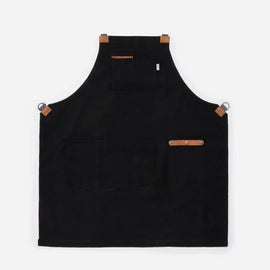 black canvas and leather chef apron with cross back straps, tool pockets, and metal hardware for cooking and grilling