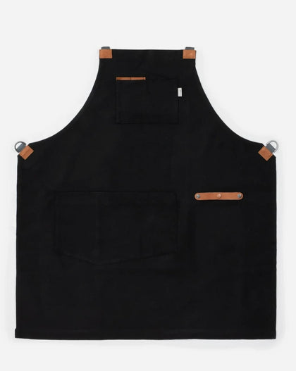 black canvas and leather chef apron with cross back straps, tool pockets, and metal hardware for cooking and grilling