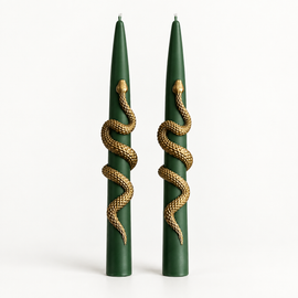 A pair of dark green taper candles with a detailed gold snake wrapped around each candle, set against a plain white background.