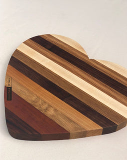Heart shaped wooden cutting board made from mixed hardwoods with natural grain patterns, perfect for charcuterie and serving