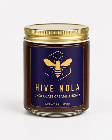 Jar of Hive Nola chocolate creamed honey with a gold lid on a white background