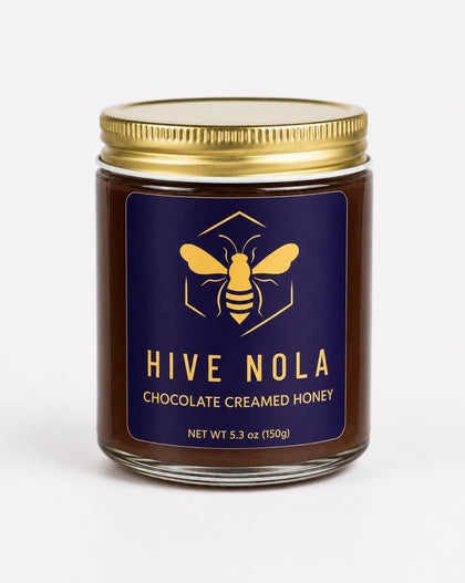 Jar of Hive Nola chocolate creamed honey with a gold lid on a white background