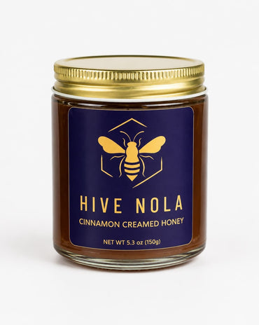 Jar of Hive Nola cinnamon creamed honey with a blue label and gold lid on a white background