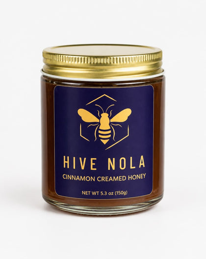 Jar of Hive Nola cinnamon creamed honey with a blue label and gold lid on a white background