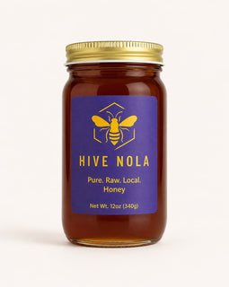 Jar of Hive Nola honey with a gold lid on a white background