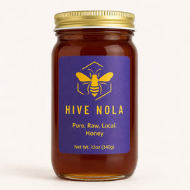 Jar of Hive Nola honey with a gold lid on a white background