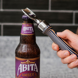 Person opening an Abita Amber beer bottle with a bottle opener.