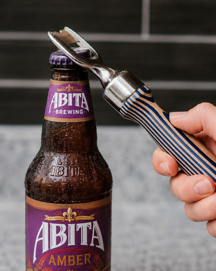 Person opening an Abita Amber beer bottle with a bottle opener.