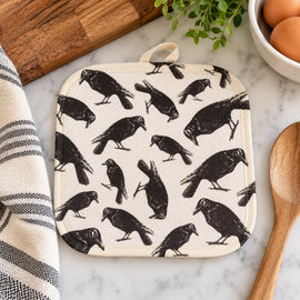 Cream pot holder with vintage-style black raven print displayed on a kitchen countertop.