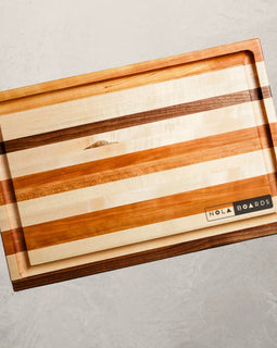 Roux mixed wood cutting board with cherry, maple, and walnut, featuring juice groove and handles, inspired by Louisiana cooking tradition