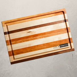 Roux mixed wood cutting board with cherry, maple, and walnut, featuring juice groove and handles, inspired by Louisiana cooking tradition