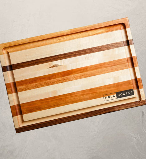 Roux mixed wood cutting board with cherry, maple, and walnut, featuring juice groove and handles, inspired by Louisiana cooking tradition