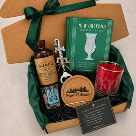 Gift set with New Orleans-themed items including a bottle, book, and coasters.
