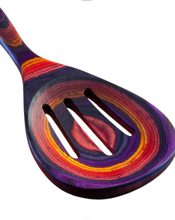 Colorful slotted cooking spoon from the Waikiki Collection, made of layered birch with vibrant purple, red, orange, and pink tones.
