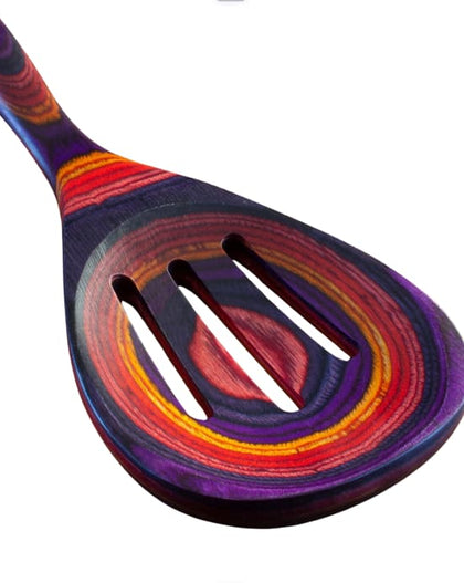 Colorful slotted cooking spoon from the Waikiki Collection, made of layered birch with vibrant purple, red, orange, and pink tones.