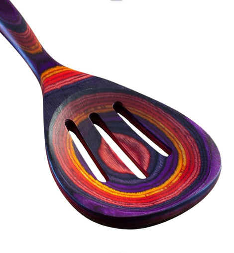 Colorful slotted cooking spoon from the Waikiki Collection, made of layered birch with vibrant purple, red, orange, and pink tones.